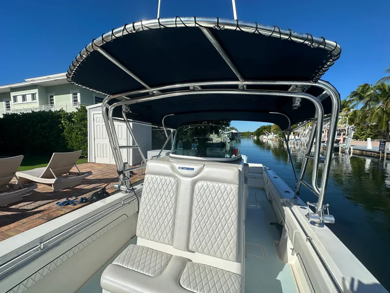 Slide: The Image of 2012 Contender 32 LS boat with T-top and cushioned seating docked by a canal. - 18