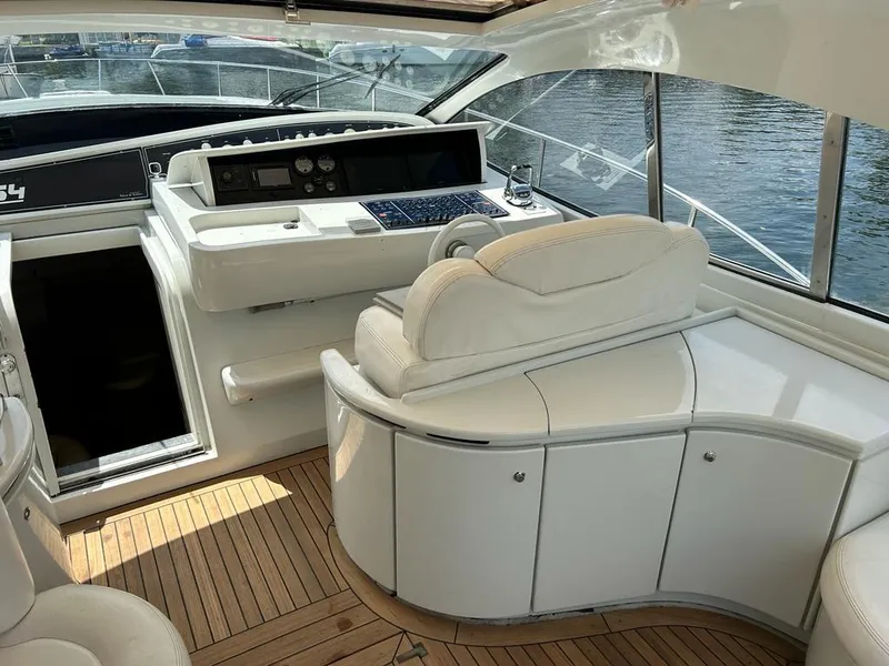 Slide: The Image of Interior helm of a 1999 Pershing 54 yacht with white seating and wooden flooring. - 7