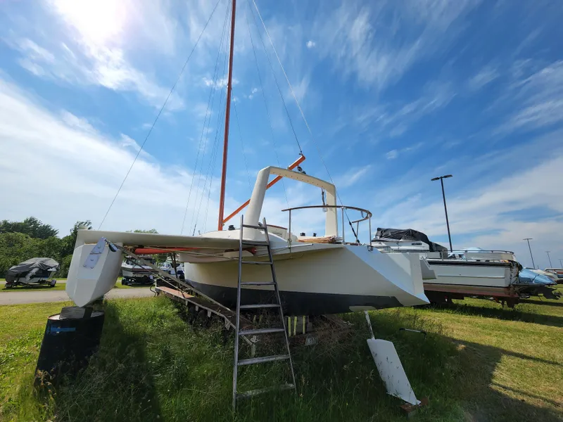 Slide: The Image of 1985 Crowther Buccaneer sailboat on grass, clear sky, ladder leaning against hull. - 1