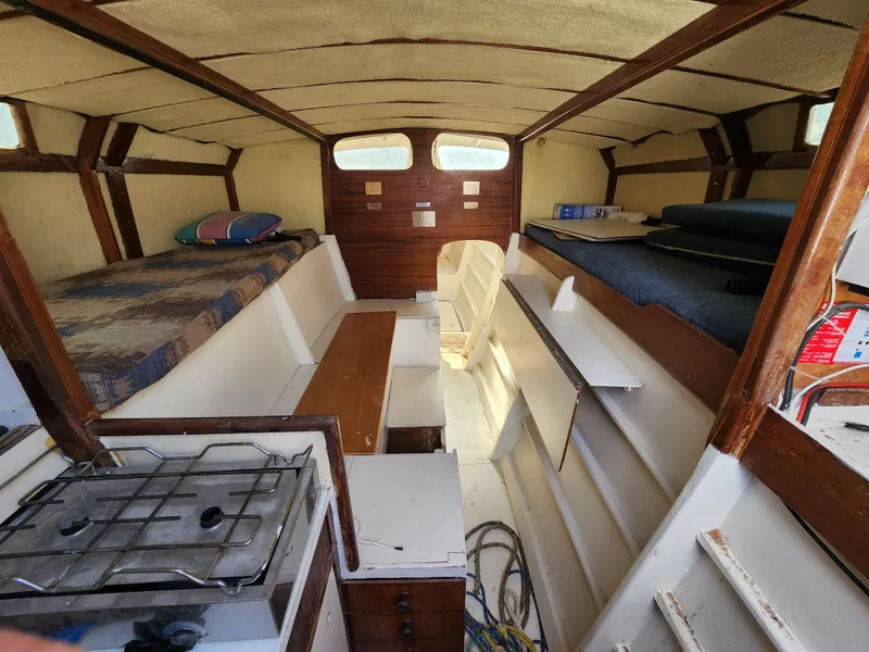 Slide: The Image of Interior of a 1985 Crowther Buccaneer boat with cozy sleeping and cooking areas. - 10