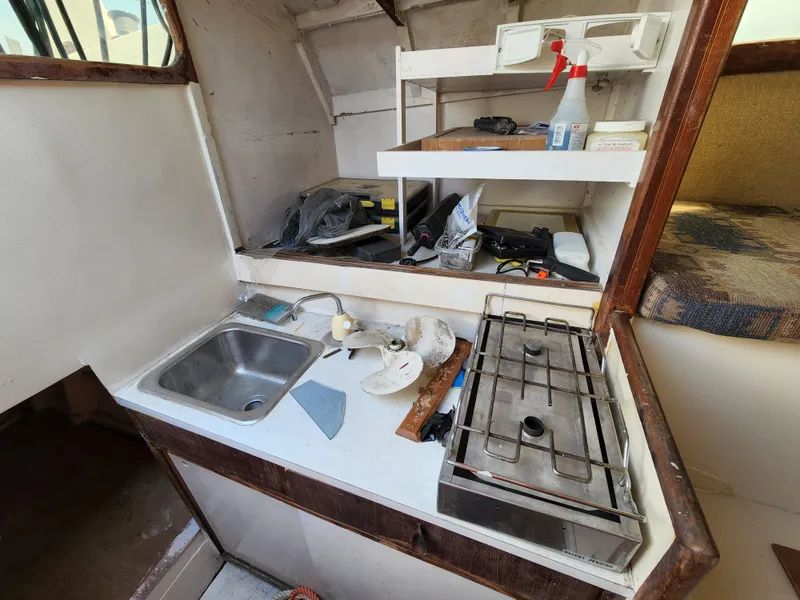 Slide: The Image of 1985 Crowther Buccaneer boat kitchen with sink, stove, and storage shelves. - 12