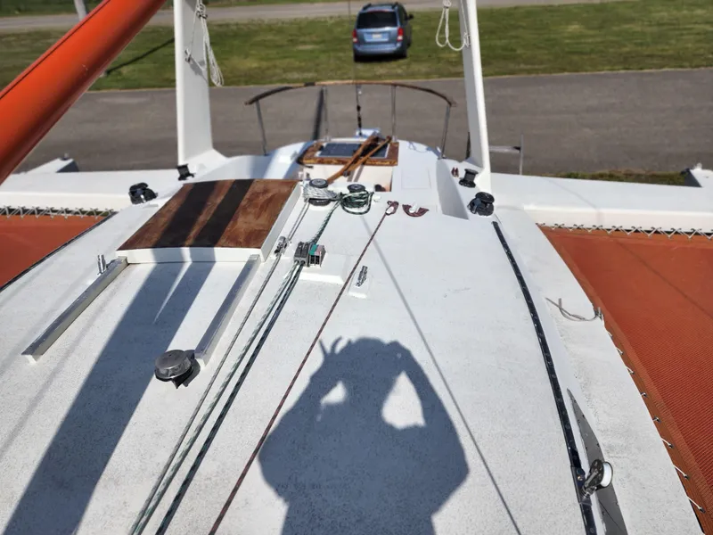 Slide: The Image of 1985 Crowther Buccaneer sailboat deck with rigging and shadow, parked car in background. - 2