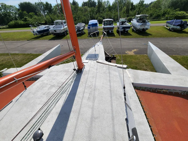 Slide: The Image of 1985 Crowther Buccaneer sailboat on land, surrounded by other boats, with visible orange mast. - 6
