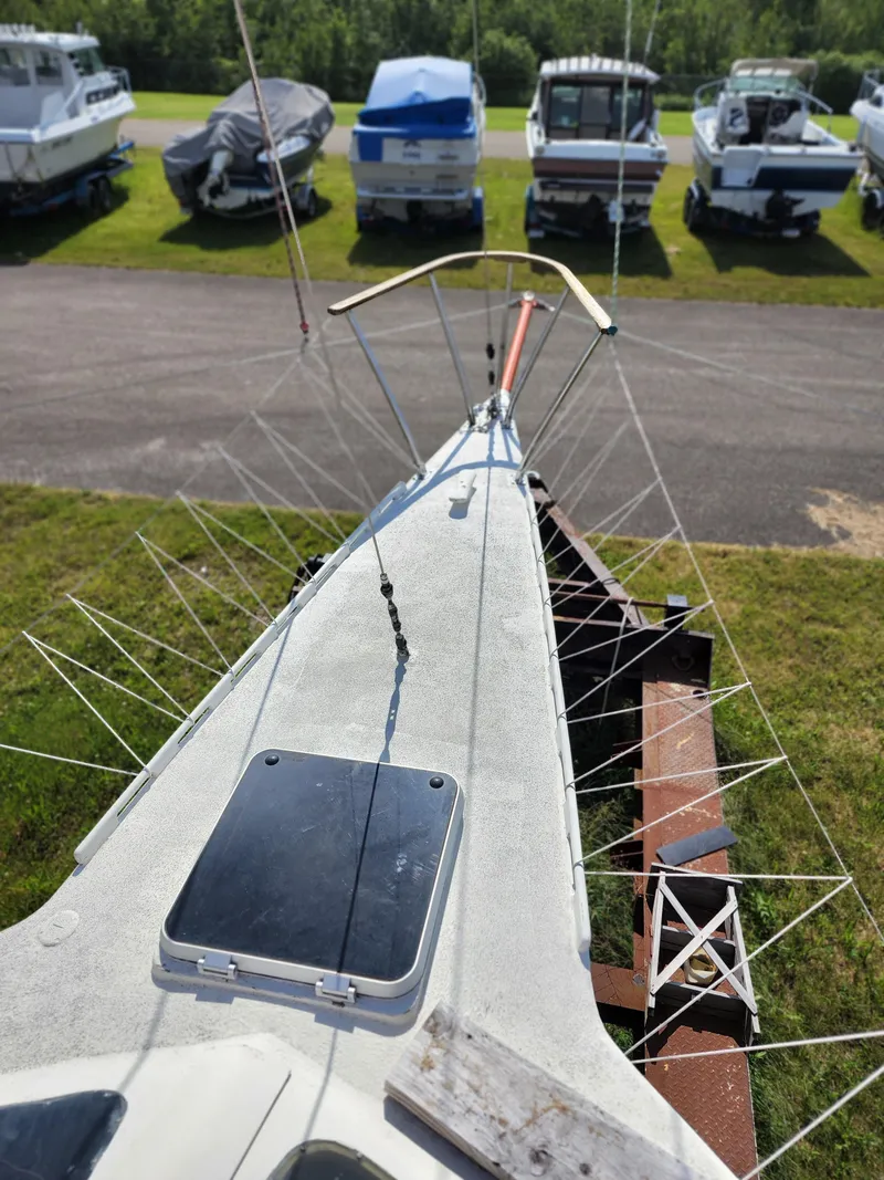 Slide: The Image of 1985 Crowther Buccaneer sailboat on trailer, surrounded by other boats in a grassy area. - 7