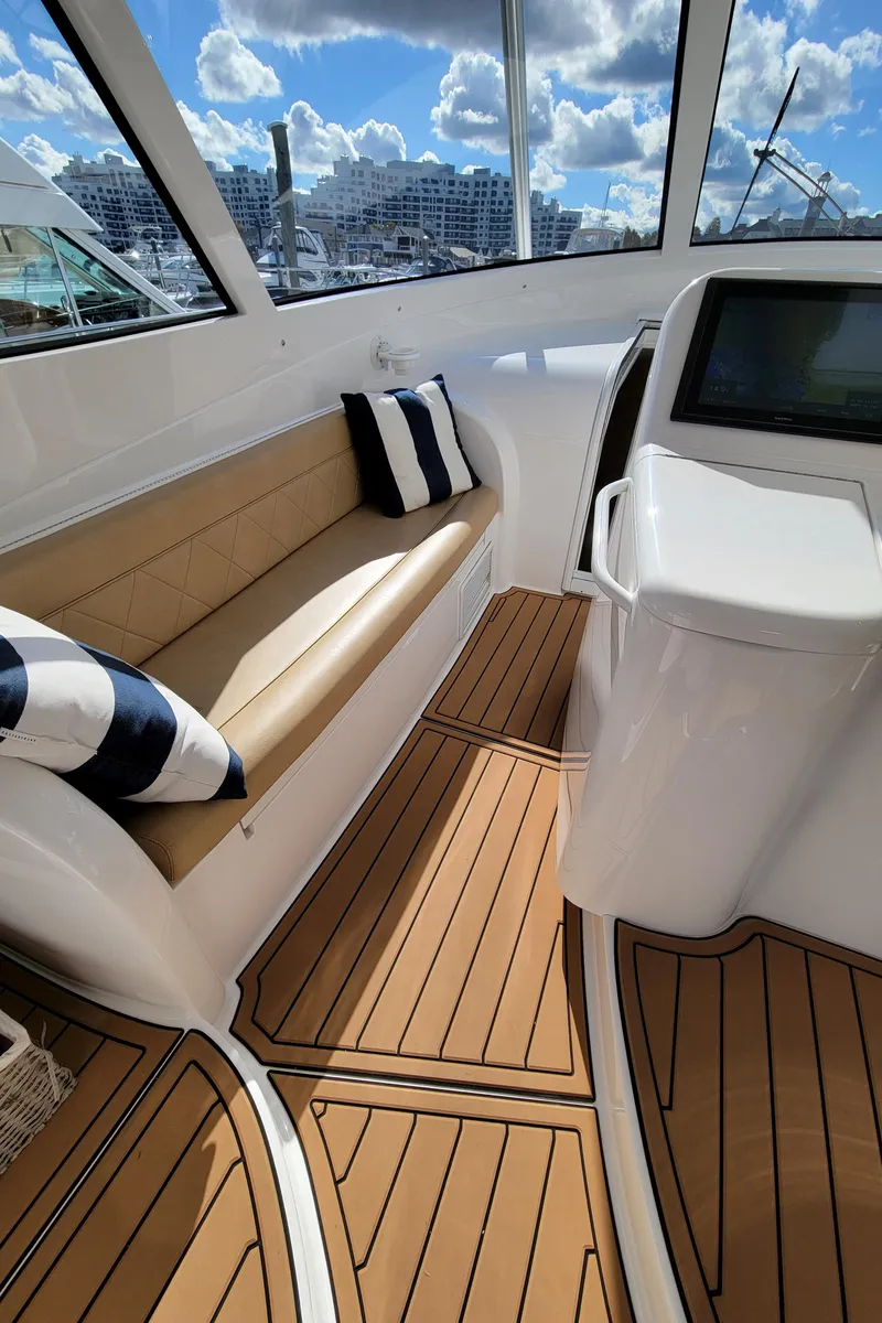 Slide: The Image of 2016 Viking 42 Sport Tower interior with tan seating and striped pillows. - 16