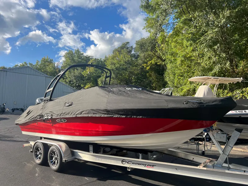 Slide: The Image of 2021 Sea Ray SPO 230 boat on trailer, covered, outdoors with trees and blue sky. - 5