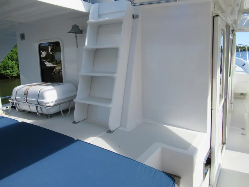 Slide: The Image of 2010 DeFever 48 Offshore yacht deck with blue cushions and white ladder. - 26