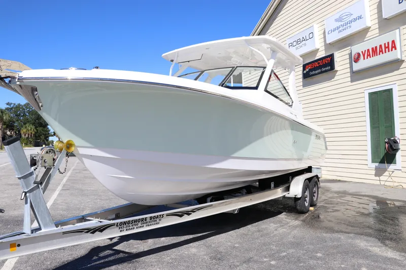 Slide: The Image of 2024 Edgewater 262CX boat on trailer outside dealership. - 2