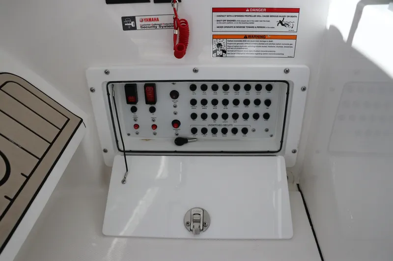 Slide: The Image of Control panel of 2024 Edgewater 262CX boat with various switches and warning labels. - 35