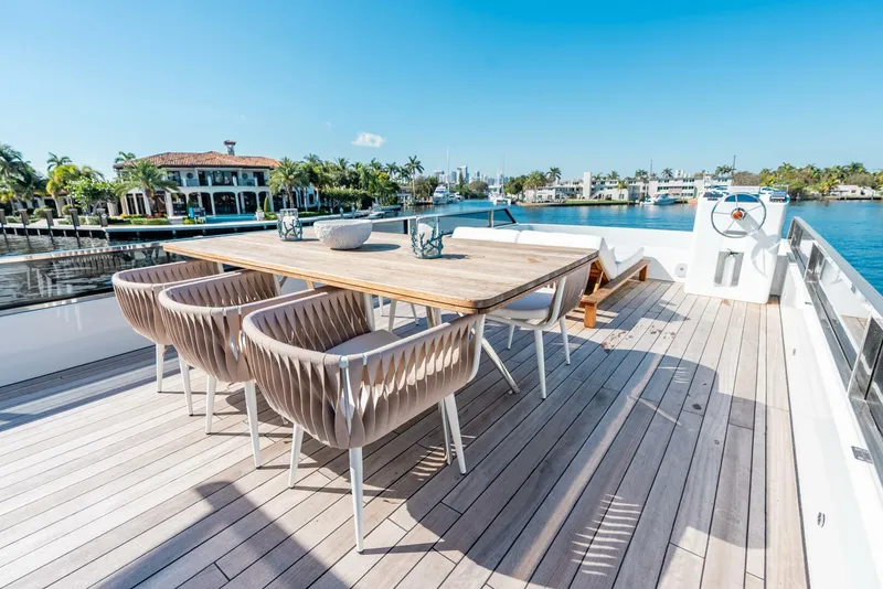 Slide: The Image of Luxury yacht deck with dining area, Reina L44 DR 2024 model, docked by waterfront homes. - 7