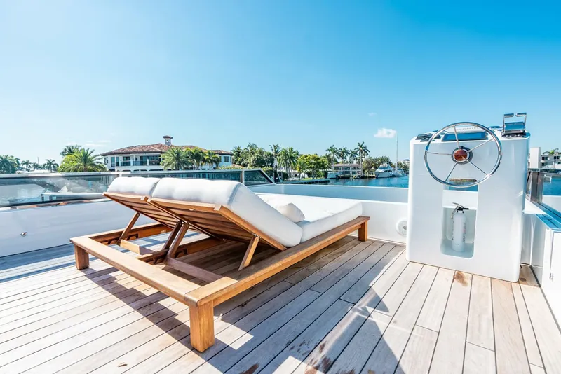 Slide: The Image of Luxury deck of Reina L44 DR yacht, 2024 model, with sun lounger and steering wheel. - 8