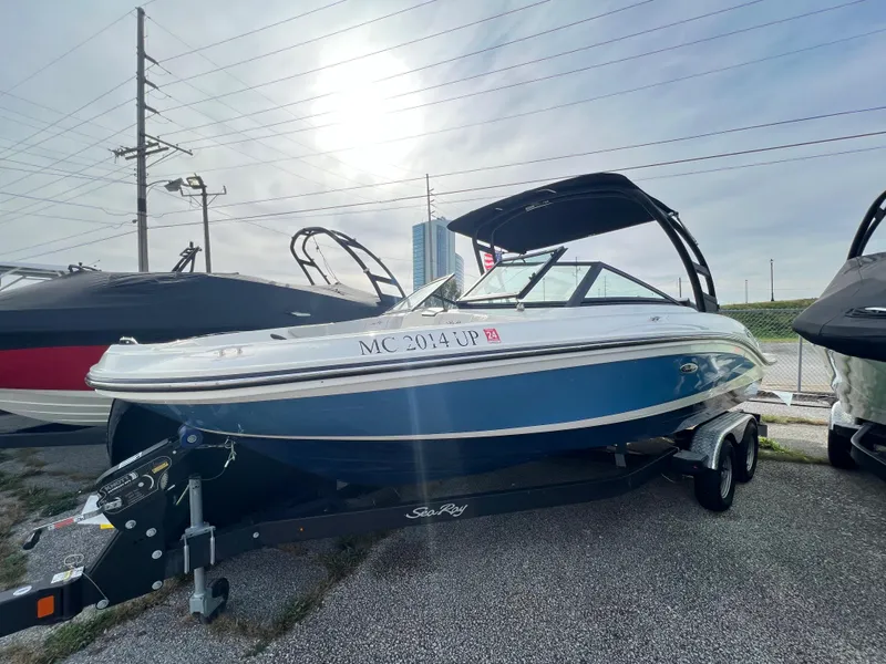 Slide: The Image of 2021 Sea Ray SPO 210 boat on trailer, blue and white, parked outdoors. - 4
