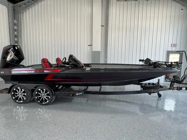 Slide: The Image of 2024 iKon LX21 black and red bass boat on a trailer in a garage. - 1