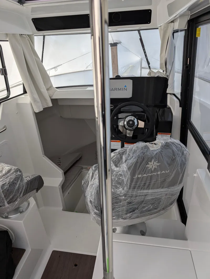 Slide: The Image of 2023 Jeanneau NC 695 Sport S2 boat interior with steering wheel and covered seats. - 7