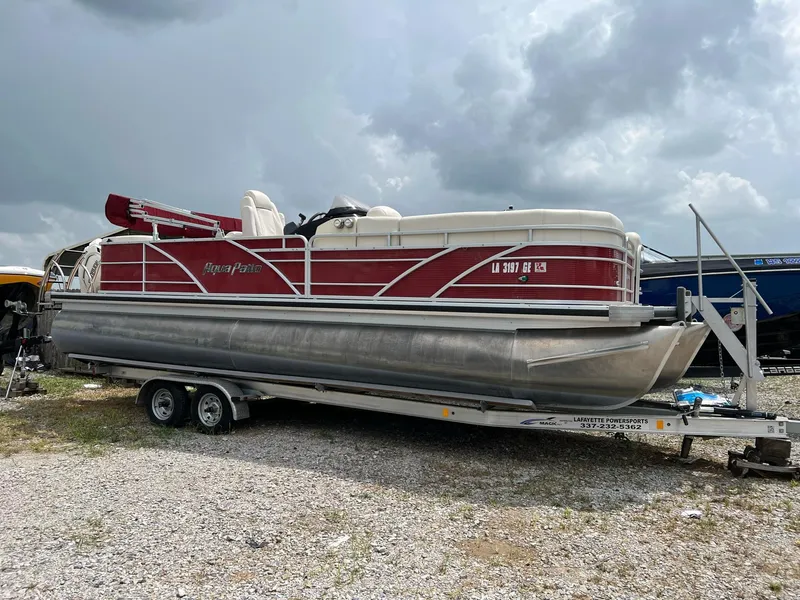 The Image of 2015 AquaPatio 240 SLR pontoon boat on a trailer under cloudy skies. - 0