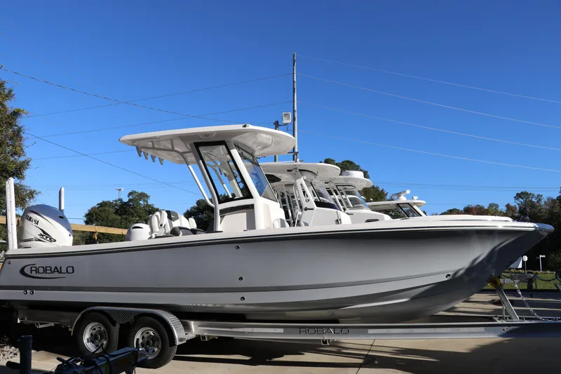 The Image of 2024 Robalo 266 Cayman boat on trailer under clear blue sky. - 0