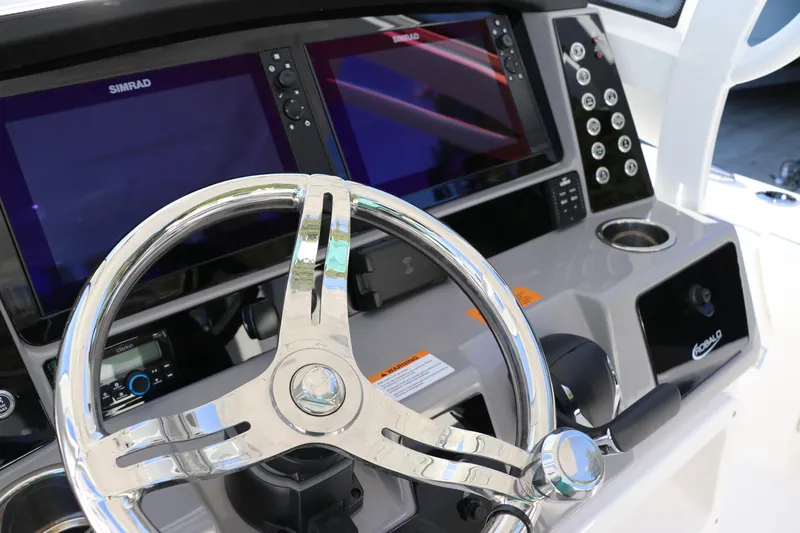 Slide: The Image of 2024 Robalo 266 Cayman boat dashboard with dual Simrad displays and chrome steering wheel. - 28