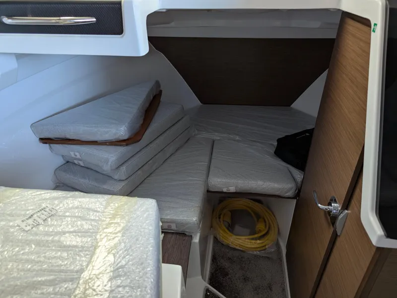 Slide: The Image of 2024 Jeanneau NC 695 Series 2 cabin interior with stacked cushions and storage space. - 9