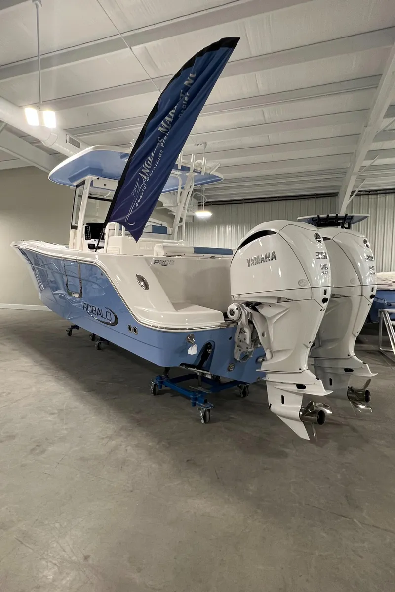 Slide: The Image of 2024 Robalo R302 boat with twin Yamaha engines in a showroom. - 2