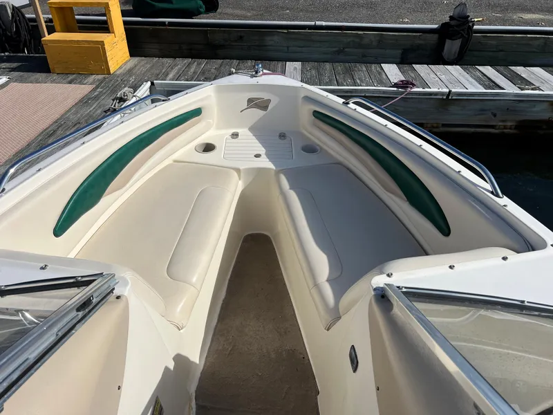Slide: The Image of 2002 Stingray 180 LS/LX boat interior with white and green seating at dock. - 2