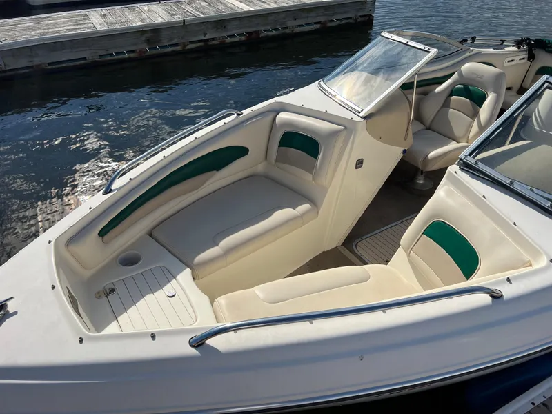 Slide: The Image of 2002 Stingray 180 LS/LX boat interior with white and green seating, docked by the water. - 8
