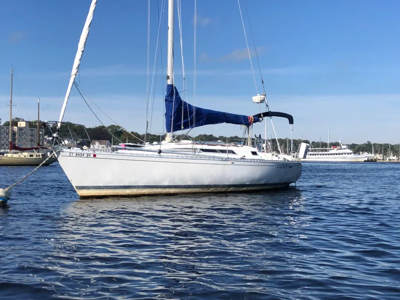 The Image of 1985 Beneteau First 345 sailboat anchored on calm water under a clear blue sky. - 0