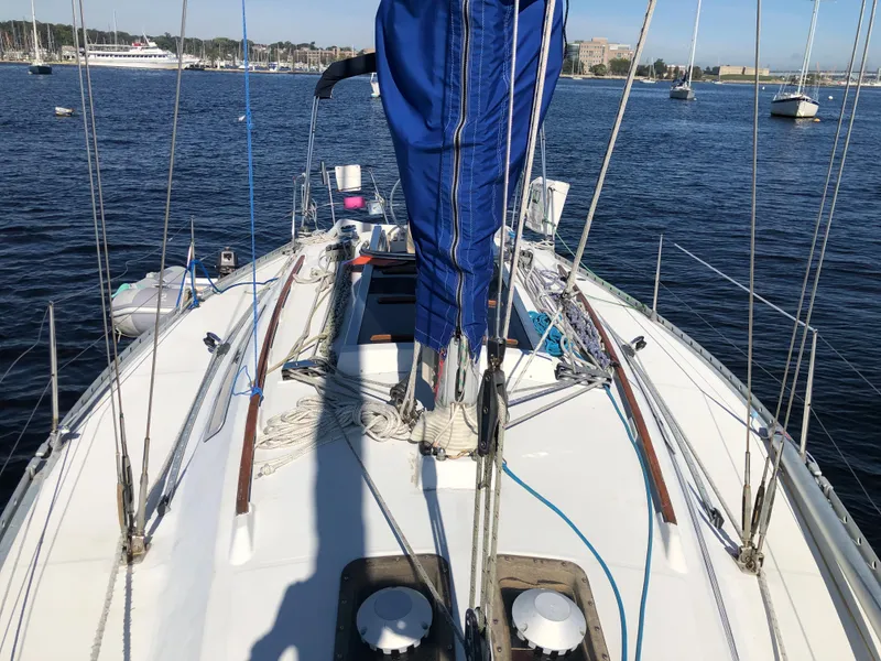 Slide: The Image of 1985 Beneteau First 345 sailboat deck with blue sail cover on calm water. - 40