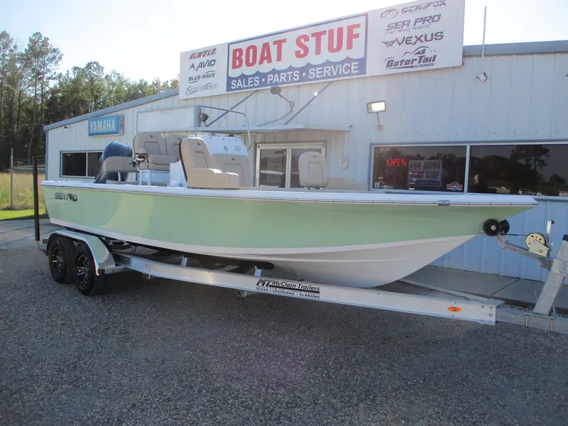 Slide: The Image of 2024 Sea Pro 228 DLX Bay boat on a trailer outside a dealership. - 1