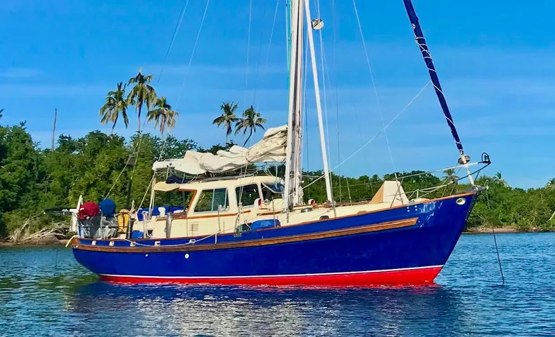 The Image of 1975 Salar 40 sailboat with blue hull anchored near tropical shoreline. - 0