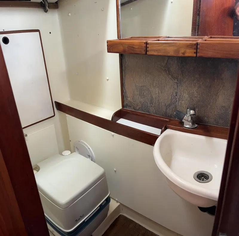 Slide: The Image of Compact bathroom in a 1975 Salar 40 boat, featuring a sink and portable toilet. - 12