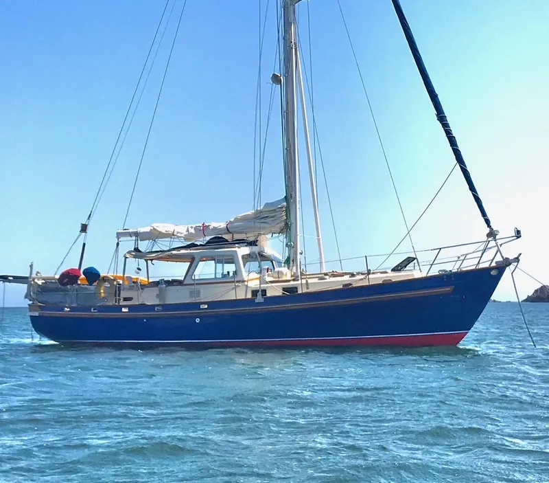 Slide: The Image of 1975 Salar 40 sailboat with blue hull anchored on calm water. - 29
