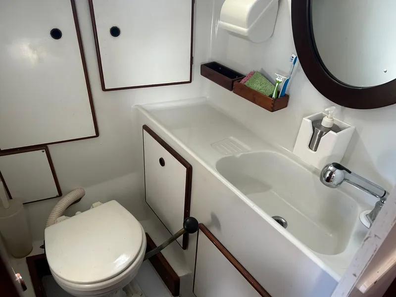 Slide: The Image of 1975 Salar 40 yacht bathroom with sink, toilet, mirror, and storage cabinets. - 6