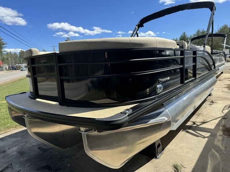 Slide: The Image of 2024 Harris Cruiser 210 pontoon boat with black exterior and beige seating. - 2