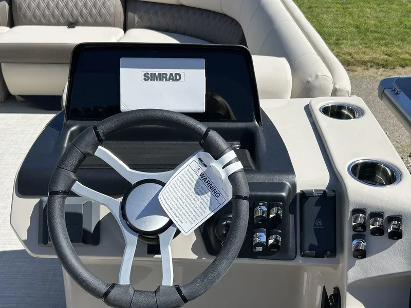 Slide: The Image of 2024 Harris Sunliner 230 boat dashboard with steering wheel and Simrad display. - 10