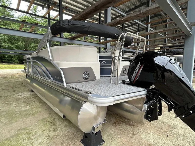 Slide: The Image of 2024 Harris Sunliner 210 pontoon boat with Mercury outboard engine, parked under a shelter. - 5