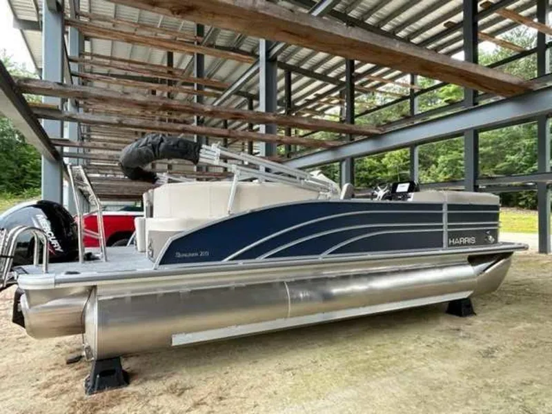 Slide: The Image of 2024 Harris Sunliner 210 pontoon boat under a metal shelter. - 9