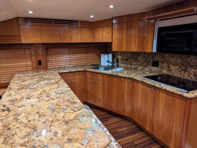 Slide: The Image of Luxurious kitchen in a 2007 Hatteras 68 Convertible yacht with granite countertops and wooden cabinetry. - 6