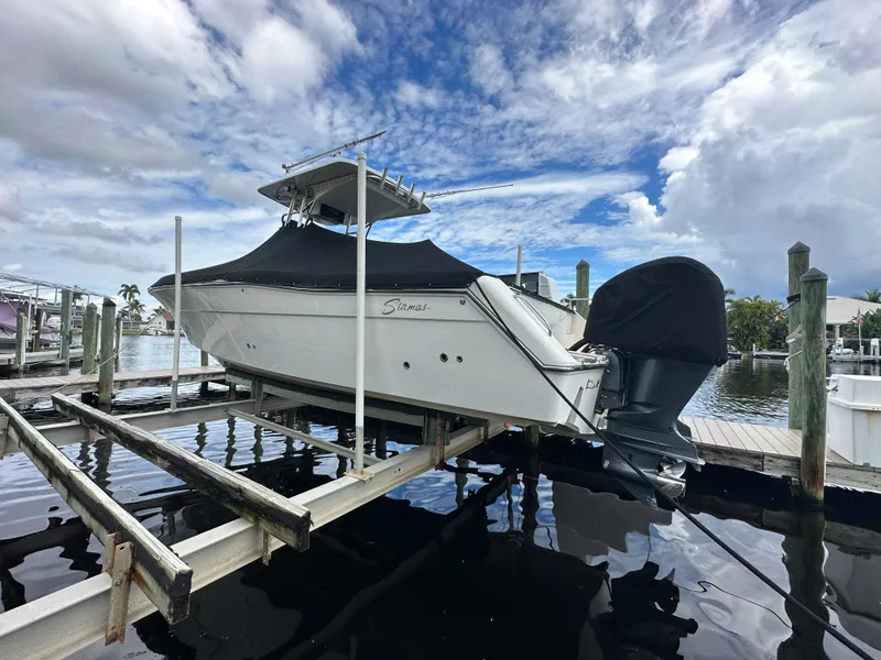 Slide: The Image of 2014 Stamas 317 Tarpon boat docked on a lift under a cloudy sky. - 4