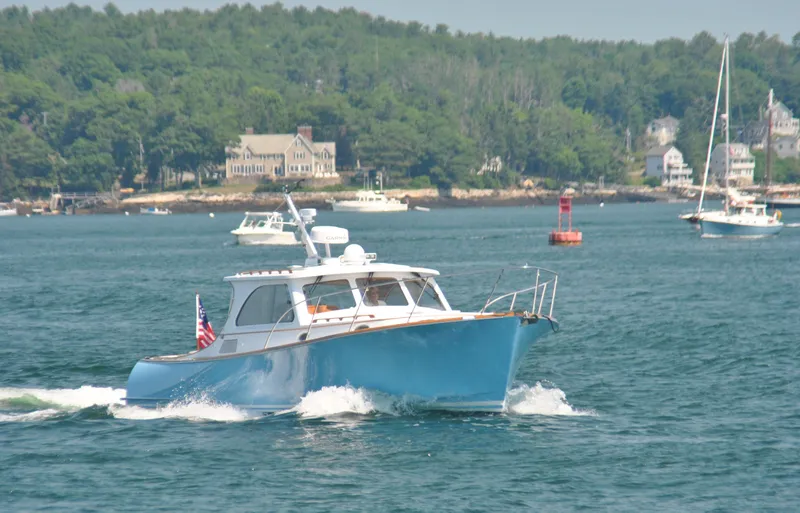 Slide: The Image of 2005 Hinckley Talaria 40 cruising on a scenic lake with lush green shoreline. - 2