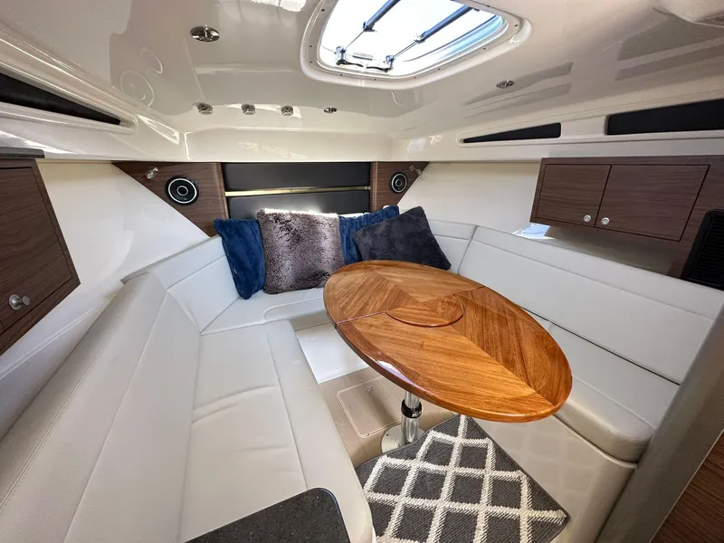 Slide: The Image of 2023 Boston Whaler 325 Conquest cabin with elegant seating and wooden table. - 10