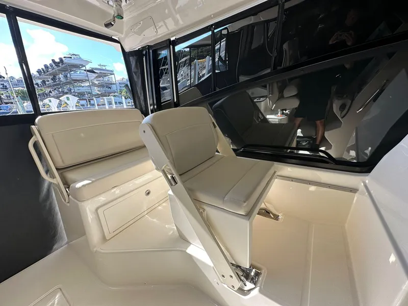 Slide: The Image of 2023 Boston Whaler 325 Conquest interior with seating and windows, showcasing luxury and comfort. - 11