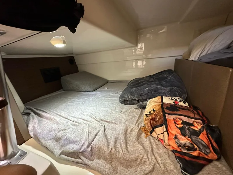 Slide: The Image of 2023 Boston Whaler 325 Conquest cabin interior with cozy bedding and soft lighting. - 15