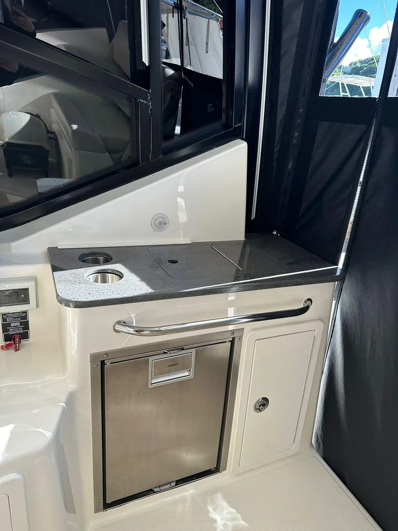 Slide: The Image of 2023 Boston Whaler 325 Conquest interior with kitchenette and storage compartments. - 16