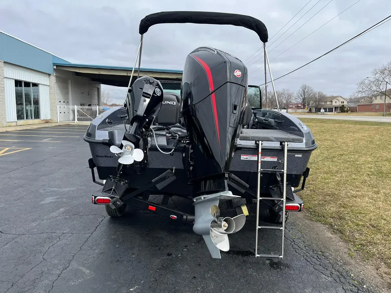 Slide: The Image of 2024 Lund 189 Tyee GL boat with dual outboard motors and ladder, parked outdoors. - 2