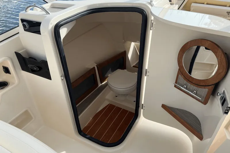 Slide: The Image of 2024 Grady-White Freedom 235 boat interior with a compact marine toilet and mirror. - 15