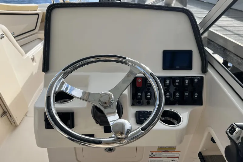 Slide: The Image of 2024 Grady-White Freedom 235 boat helm with steering wheel and control panel. - 18