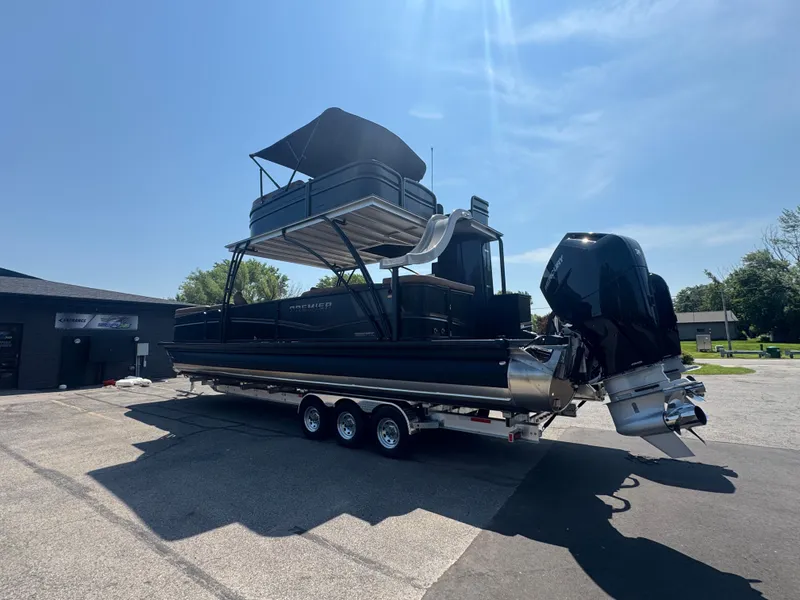 Slide: The Image of 2026 Premier Escalante pontoon boat with dual engines on a trailer, under clear blue sky. - 3
