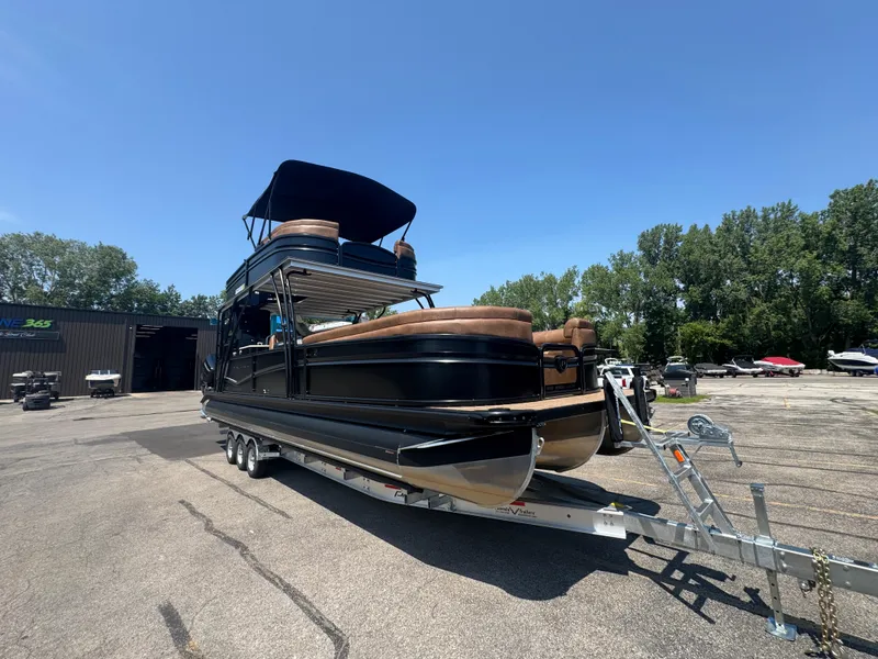 Slide: The Image of 2026 Premier Escalante pontoon boat on trailer, parked outdoors under clear blue sky. - 7