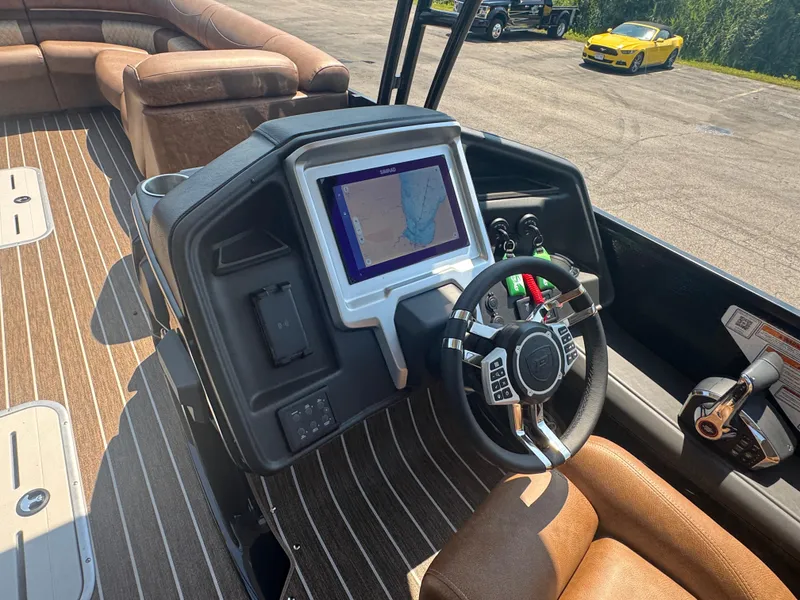 Slide: The Image of 2026 Premier Escalante boat dashboard with navigation screen and steering wheel, brown seating, outdoor setting. - 9