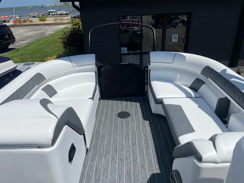 Slide: The Image of 2024 Premier Supersport boat interior with white seating and gray flooring, docked near a waterfront. - 14